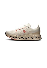 Beige running shoe with a textured upper, featuring red accents, a distinctive rounded sole, and cutouts for breathability.