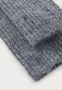 Grå stickad tyglager som visar ett texturerat mönster med en mjuk, fluffig utseende, idealiskt för värme och komfort.