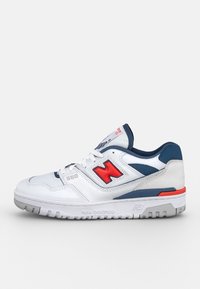 Basket New Balance 550 blanche avec logo rouge, accents bleu marine, semelle grise et lacets blancs, vue de côté extérieur.