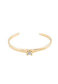 Pulsera de oro con un diseño de banda suave y delgada, adornada con un solo diamante redondo en el centro, que presenta un engaste en forma de flor.