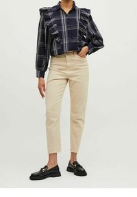 Navy checkered shirt with ruffled shoulders, paired with light beige fitted pants and black loafers featuring a gold accent.