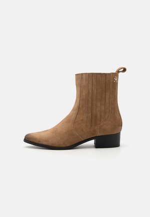 Bottine en daim marron avec petit talon bloc noir, empiècement élastique latéral et languette à l'arrière.