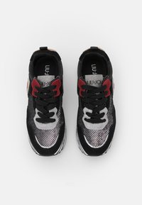 Sneaker nere con pannelli in rete argentata, dettagli rossi e lacci neri. Presentano un design elegante e superfici testurizzate. Logo sulla linguetta.