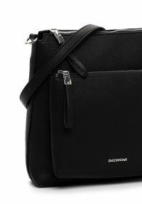 Borsa a mano in pelle nera con superficie testurizzata, dettagli in argento, tracolla regolabile e tasca frontale con zip. Etichetta del marchio visibile sul davanti.