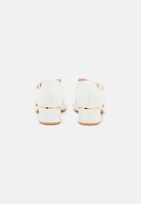White heels with a smooth leather finish, square heels, and a gold accent on the heel base; feature a buckle closure at the ankle.