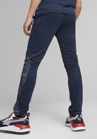 Marina atletiska byxor med en skräddarsydd design, med en texturerad sidopana i mörkblått med röda accenter. Slät tyg, smal ben.