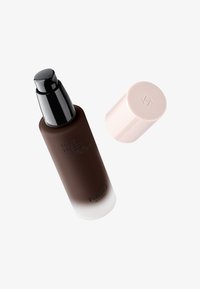 Flacon-pompe fermé de couleur brun foncé avec distributeur noir et capuchon beige pâle détaché, marqué KIKO Milano, incliné sur fond blanc.