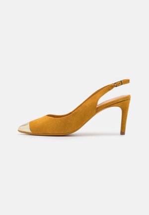 Chaussure à talon haut slingback en daim jaune avec embout pointu métallique doré et bride réglable avec boucle.