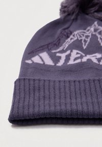 Berretto lavorato a maglia viola con un bordino a coste, caratterizzato da un design ricamato di montagne e un pom-pom sulla sommità, realizzato in materiale morbido e testurizzato.