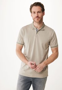 Lys beige polo shirt i blødt bomuldsblanding med korte ærmer, en krave og diskrete striber langs kraven og ærmerne.