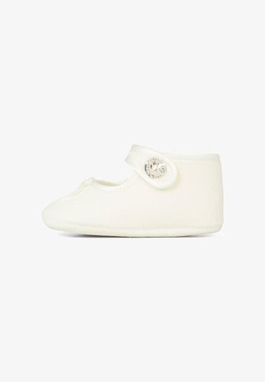 Pantofole in pile bianco con punta arrotondata, cinturino regolabile e dettaglio decorativo con bottone. Texture morbida e design minimalista.