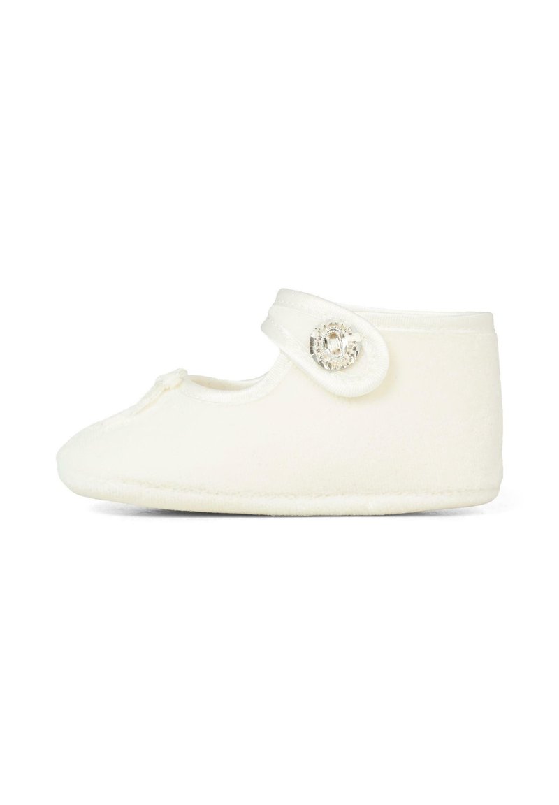 Pantofole in pile bianco con punta arrotondata, cinturino regolabile e dettaglio decorativo con bottone. Texture morbida e design minimalista.
