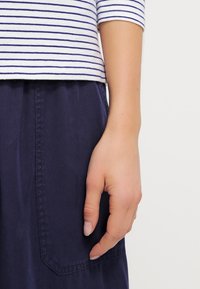 Randig bomullsskjorta i vitt och marinblått, med korta ärmar, kombinerad med marinblå tygshorts med sidofickor och en mjuk yta.