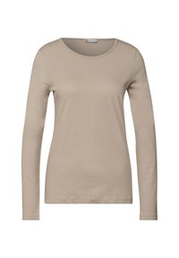 Beige långärmad skjorta i mjukt tyg. Har en rund halsringning och en figurnära passform med ensartad struktur utan synliga mönster eller detaljer.