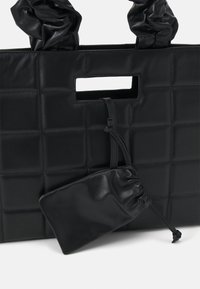 Borsa a tote nera trapuntata con manici arricciati, dotata di un taglio rettangolare e di una pochette staccabile con chiusura a coulisse.