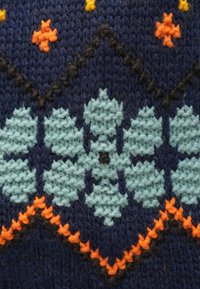 Wzór dzianiny na ciemnoniebieskim tle z turkusowymi kwiatami, pomarańczowymi akcentami i czarnymi konturami, ukazujący teksturę i kunszt wykonania.