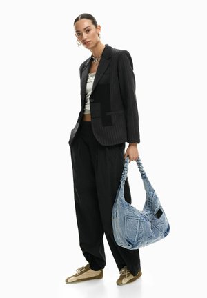Fekete tűsarkú blézer kontrasztos folttal, laza fekete nadrággal, fehér felsővel és világoskék farmer hobo táskával párosítva.