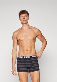 Fekete és szürke csíkos boxer alsónadrág, elasztikus derékkal, amelyen fehér "PUMA" felirat található. Testhezálló forma, rugalmas anyagból.