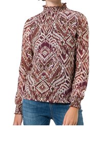 Blouse à manches longues avec un col haut et volanté, présentant un motif géométrique bordeaux et crème, et des poignets froncés. Tissu doux et léger.