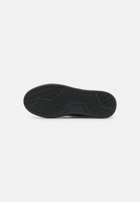 Suola di scarpa in gomma nera con motivo di grip testurizzato, tacco arrotondato e design con supporto arcato. Caratterizzata da battistrada pronunciato per migliorare la trazione.