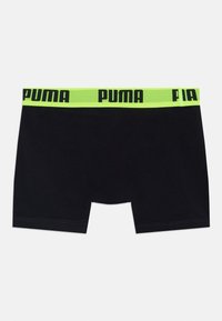 Črne bombažne bokserice z neon zelenim pasom, ki ima črn logotip "PUMA". Gladka tekstura, dolžina do sredine stegen z odločeno obrobljenimi robovi.