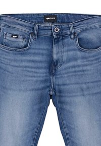 Jeans de mezclilla azul con un lavado medio, con cierre de botón, cinco bolsillos y costuras en contraste. Etiqueta de logo visible en la cinturilla.