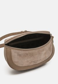 Bolso bandolera de ante marrón con forma redondeada, cierre de cremallera y una sola correa. El interior cuenta con un bolsillo y un forro texturizado.