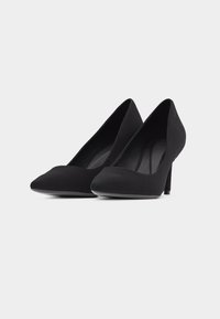 Ζευγάρι μαύρα γόβες με μυτερή μύτη και τακούνι στιλέτο σε λευκό φόντο.