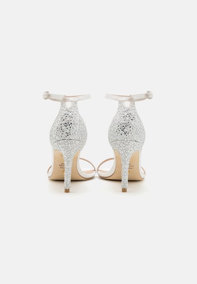 Belles sandales ouvertes en argent brillant, ornées de strass scintillants, avec des brides délicates à la cheville et un talon aiguille modéré.