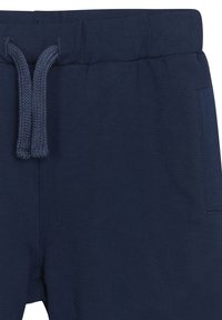 Pantaloni in cotone blu navy con vita regolabile tramite laccetto, caratterizzati da un tessuto loopato testurizzato, fascia elastica in vita e tasca laterale.