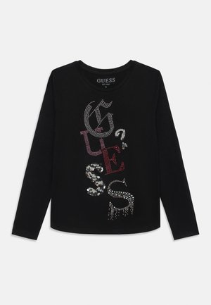 Sort langærmet skjorte med vertikal "GUESS"-tekst i pailletter og rhinsten i forskellige farver og stilarter midt på forsiden.