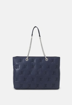 Sac fourre-tout en cuir marine avec motif gaufré "J!", poignées doubles avec accents en chaîne argentée, forme rectangulaire, texture lisse.