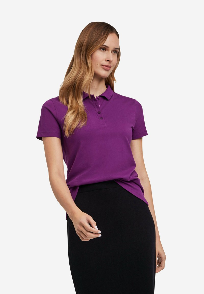 Paarse poloshirt met korte mouwen, knoopsluiting met drie knopen en een relaxte pasvorm, gecombineerd met een zwarte rok. Soepele textuur, effen kleur.