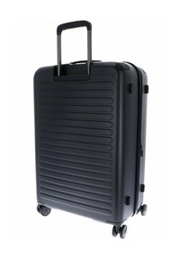 Valise rigide noire avec texture nervurée, poignée rétractable, deux roues et fermeture éclair. Design rectangulaire compact pour les voyages.