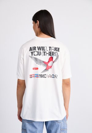 T-shirt en coton blanc présentant un graphisme coloré d'un oiseau, le texte « AIR WILL TAKE YOU (THERE) » et le logo Nike, avec une coupe décontractée.
