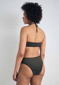 Črn in zlati bleščeči bikini s bandeau zgornjim delom in visokim pasom. Ima vrata za halter in gladko, teksturirano tkanino.