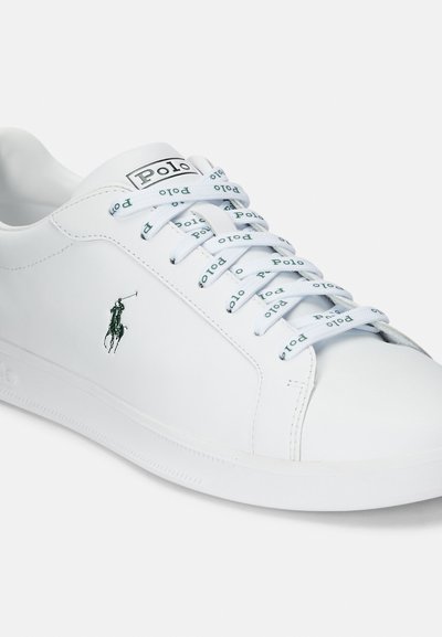 Baltas ādas sporta apavu modelis ar gludu tekstūru, zaļš izšuvums logos un rakstainas šņores ar zaļu tekstu "Polo". Plakana gumijas zole.