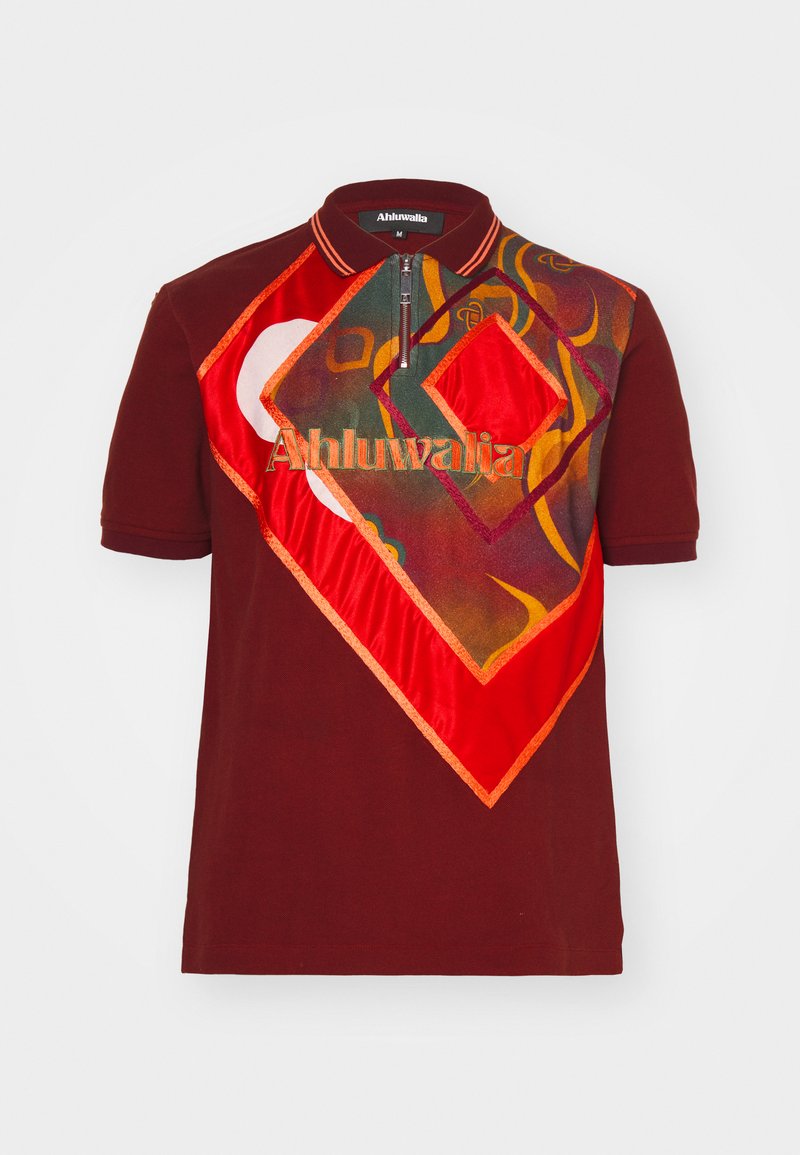 Polo bourgogne à manches courtes et zip quart, avec des motifs géométriques multicolores et un logo brodé en orange.