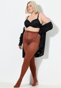 Medias marrones con textura acanalada, combinadas con un sujetador negro y un chal negro translúcido, presentando un acabado opaco y textura acanalada vertical.