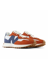 Zapatillas con una parte superior de ante en blanco y naranja, acentos azules y cordones blancos. Suela de goma texturizada con un diseño robusto para agarre.