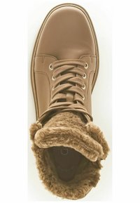 Brązowy skórzany but z sznurowadłami, z miękkim, sztucznym futerkiem w okolicy kołnierza i okrągłym noskiem. Widoczne otwory na sznurowadła oraz detale szycia.
