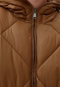 Brązowa puchowa kurtka z zamkiem z przodu, wyposażona w kaptur i diamentowy wzór pikowania. Gładka tekstura i kontrastowy czarny zamek.