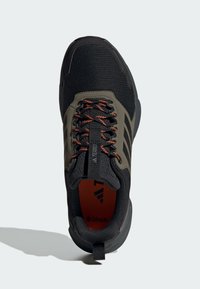 Schwarzer athletic Schuh aus Netzmaterial, mit grauen Akzenten und orangefarbenen Schnürsenkeln. Verfügt über einen gepolsterten Kragen, eine strukturierte Sohle und ein auffälliges Logo-Detail.