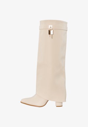 Bota de cuero beige hasta la rodilla con punta cuadrada, tacón grueso y detalle de candado dorado cerca del borde superior.