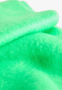 Mehka, svetlo zelena filcasta tkanina z puhasto teksturo in subtilnimi barvnimi in svetlobnimi odtenki.