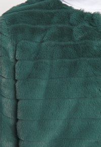 Tessuto in pelliccia sintetica di colore verde scuro con un motivo a strisce testurizzato. Superficie morbida e plush con una leggera lucentezza e lunghezze di pelo variabili.