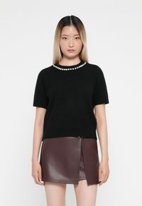 Black short-sleeve sweater with a pearl accent neckline, paired with a burgundy leather mini skirt featuring a diagonal zipper detail.
