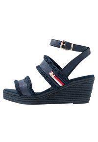 Sandali wedge navy con cinturini in tessuto e pelle, caratterizzati da un bordo sfilacciato, un accento a righe e una suola intrecciata. Cinturino alla caviglia regolabile.