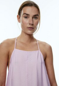 Helles rosa ärmelloses Top mit dünnen Trägern, das aus einem strukturierten Stoff gefertigt ist und eine lockere Passform hat. Es ist mit einem geraden Ausschnitt und dezenten Falten gestaltet.