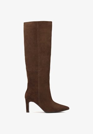 Brązowy zamszowy botek do kolan z ostro zakończonym noskiem i obcasem szpilką. Posiada gładką teksturę i minimalne detale szwów wzdłuż boku.